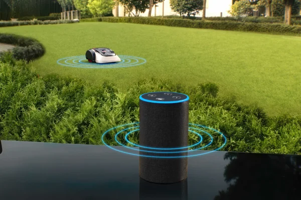 Smart speaker sends voice commands to robotic mower in the yard.