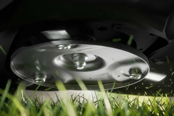 Close view of spinning cutting disc and blades beneath mower.