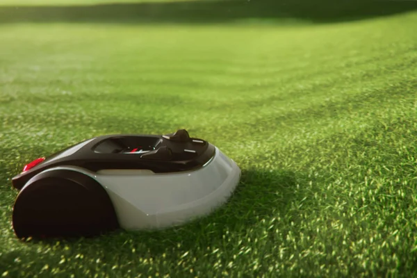Low side view of robotic mower moving smoothly through dense green grass.